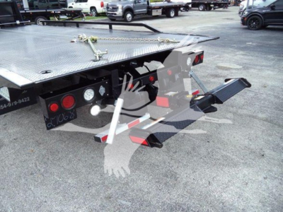 Rear view of a 2023 Chevrolet Silverado 6500HD rollback truck showing tow hitch, hydraulic controls, and heavy-duty flatbed with diamond plate surface.