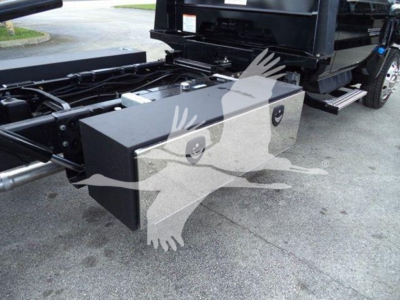 Truck chassis rear view showing toolbox/bed side box mounted near the truck frame with storage compartments and hydraulic lines.