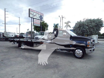 Tow truck flatbed with Chevrolet Silverado 6500HD branding visible in Lot setting; clear side view with extended flatbed and chrome wheels.