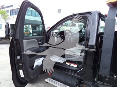 Truck cab interior visible with open driver door showing steering wheel, dashboard, and seat; no discernible labels or text clearly readable inside.