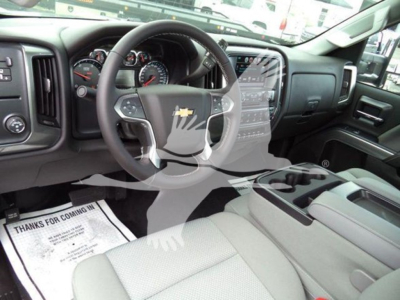 Interior of a Chevrolet Silverado pickup truck: steering wheel with Chevrolet emblem, dashboard, center console, gear shifter area; driver seat; faint printed floor mat.