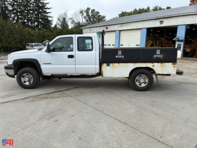 Chevrolet Silverado 2500 utility truck side view showing white cab, extended steel flatbed with rust and tool boxes.