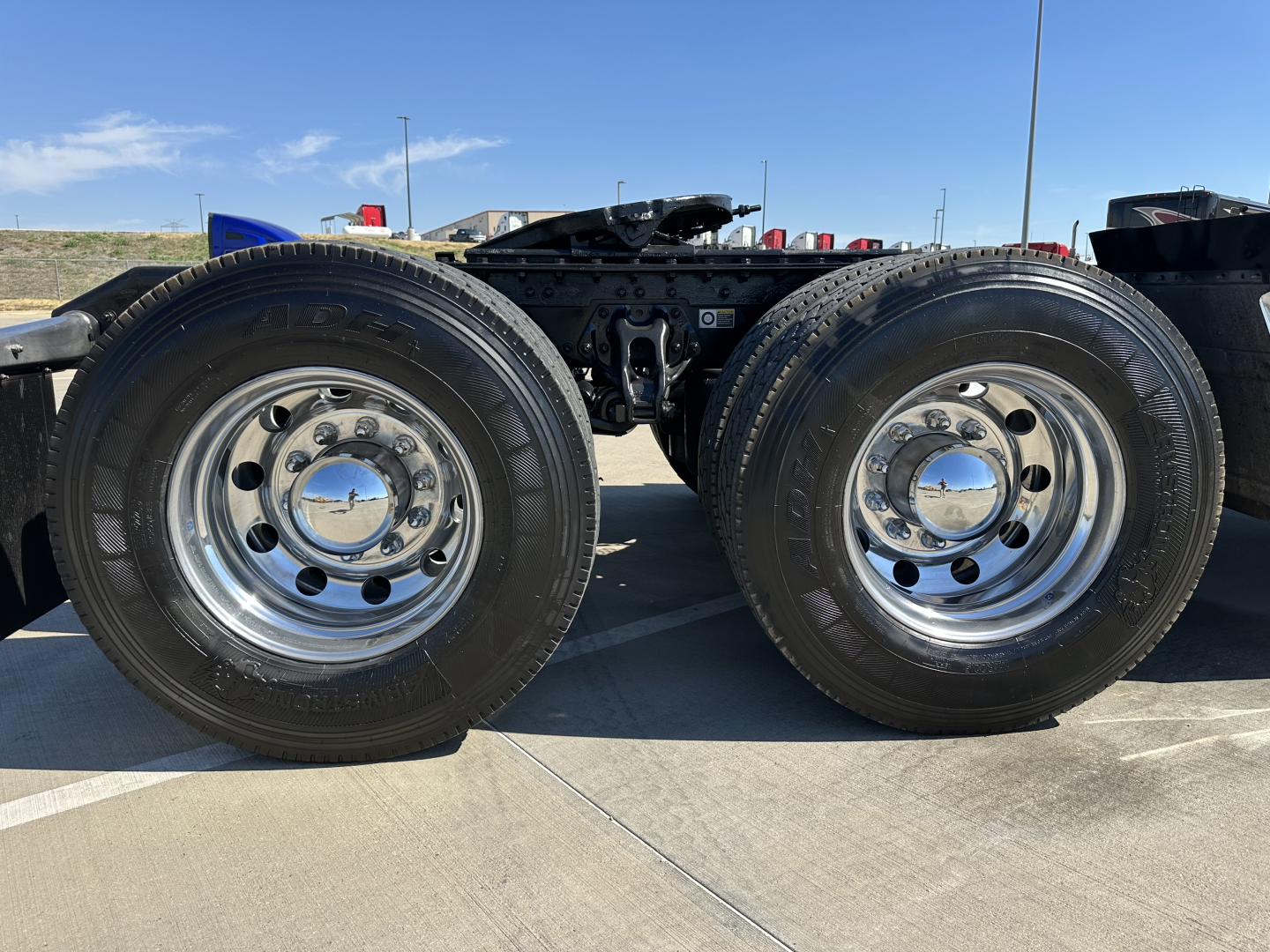 Kenworth T680 chassis with dual rear axles and large chrome wheels, visible tires and wheel hubs, undercarriage framing and fifth wheel area in view.