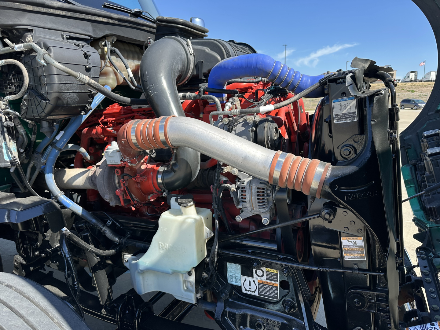 Kenworth T680 engine bay showing turbo hoses, radiator, and engine components.