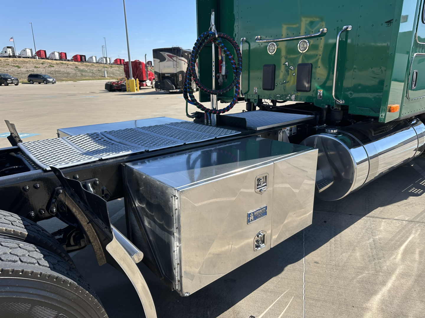 Kenworth T680 sleeper cab tractor with chrome fuel tanks and aluminum tool box mounted behind cab showing metal diamond plate deck and green cab paint.