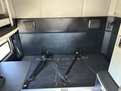 Kenworth T680 sleeper cab interior cargo area with tie-downs and black flooring.