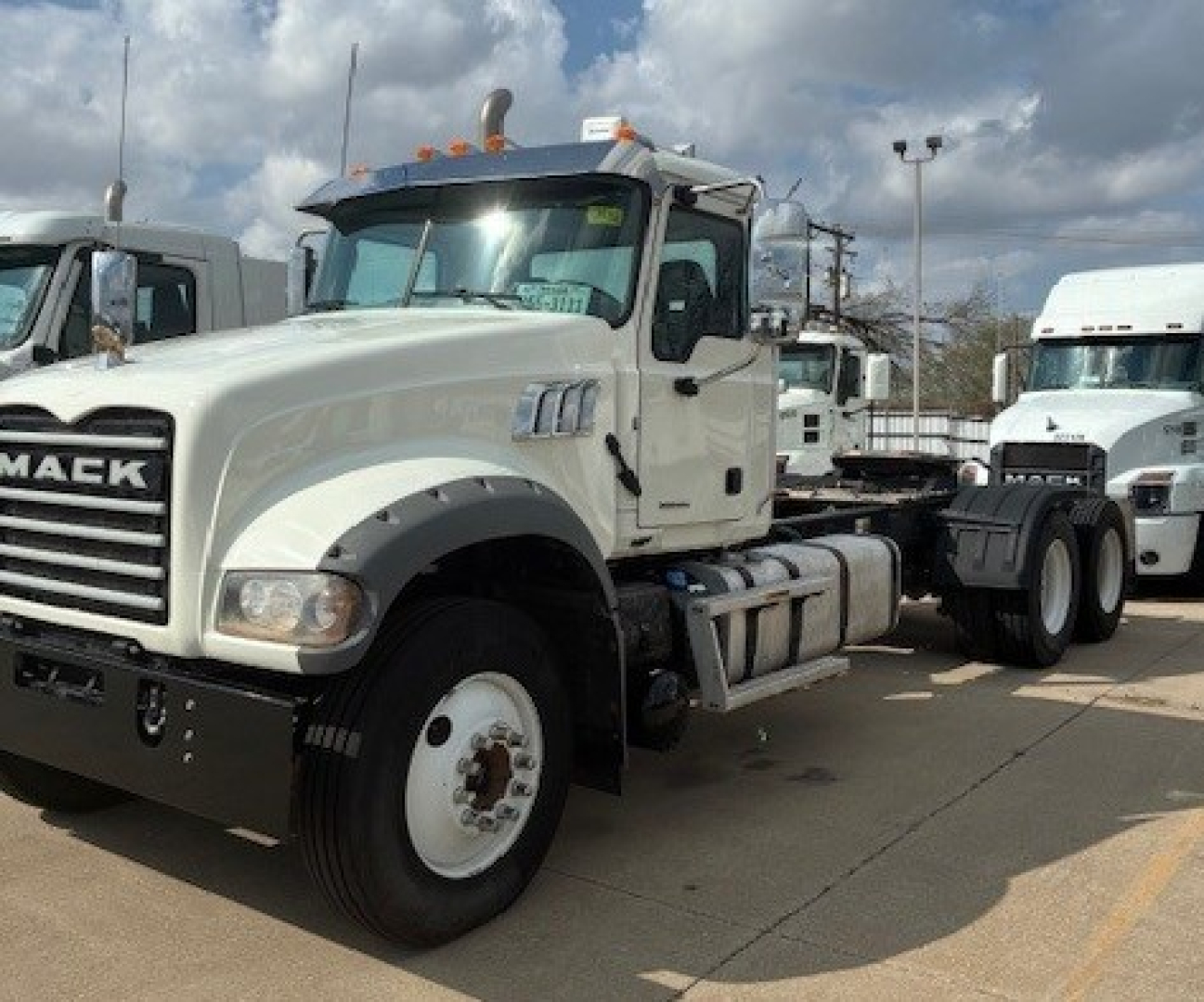 Mack GR64FT conventional daycab tractor showing front-left view with white cab and black grille.