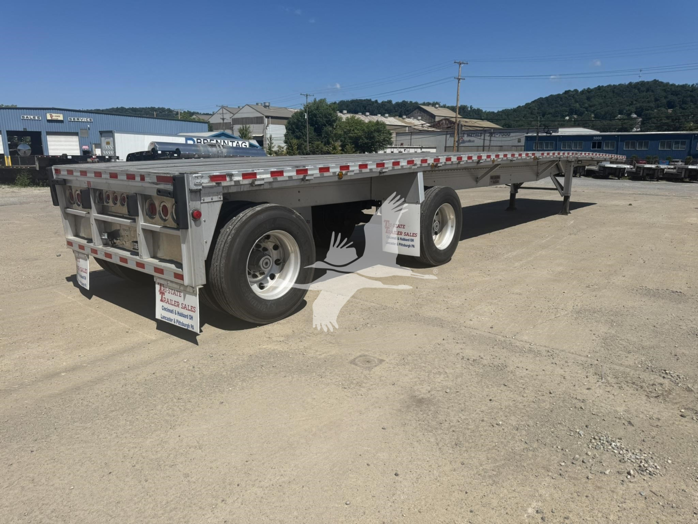 Flatbed trailer showing dual rear axles with_rear Underside 2022 Reitnouer Big Bubba trailer, with side markings and rear taillights.