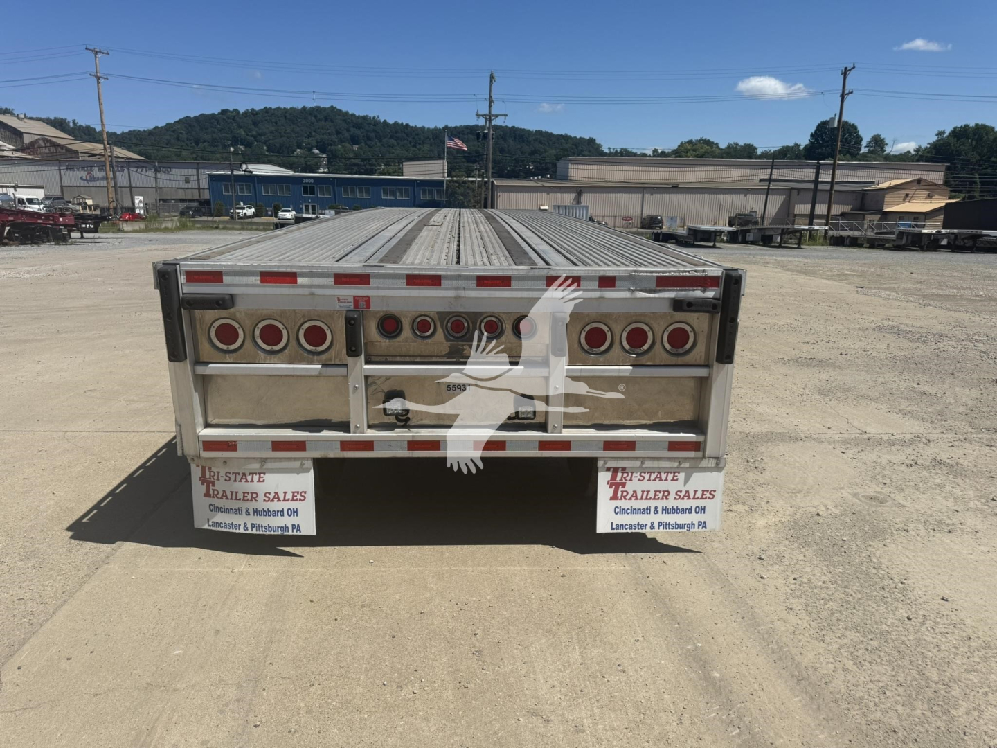 Rear view of a 2022 Reitnouer Big Bubba flatbed trailer showing multiple circular taillights, rear bumper, and signs saying 'State Trailer Sales' on both sides. Flatbed surface extends to the back.