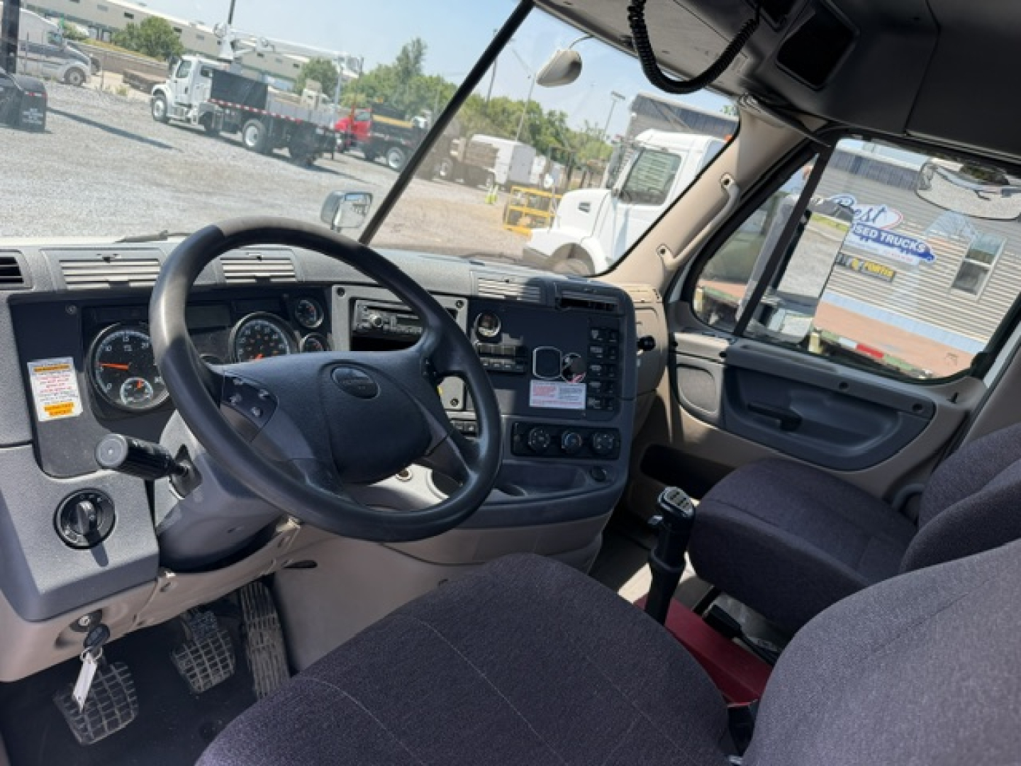 Cab interior of a 2017 Freightliner Cascadia CA125DC showing steering wheel, dashboard gauges, and gear shift.