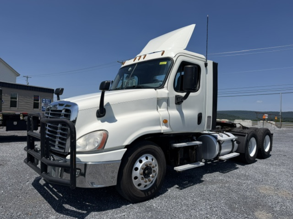 Truck cab shows Freightliner Cascadia CA125DC with white exterior, front grille guard, side mirrors, and flatbedless tractor configuration.