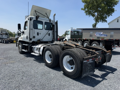Freightliner Cascadia CA125DC tractor truck rear/from side with fifth wheel and dual rear axles visible.