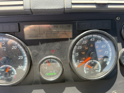 Dashboard of a Freightliner Cascadia showing speedometer, tachometer, fuel gauge, and digital readout. Visible text includes 'RPM X1000', 'MPG 4.3', and various gauge markings.
