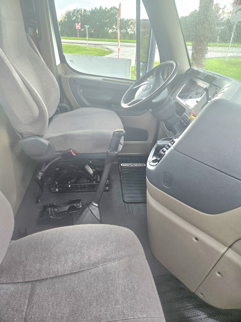 Interior cab of 2017 Freightliner Cascadia single axle daycab showing steering wheel, driver seat, manual gear shifter, and dashboard in view.