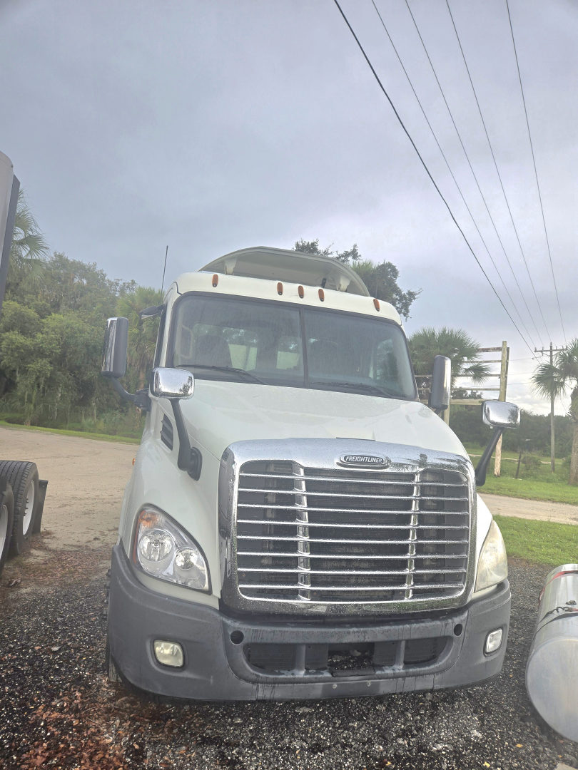 Truck front view showing Freightliner Cascadia cab with chrome grille, large bumper, and dual side mirrors.