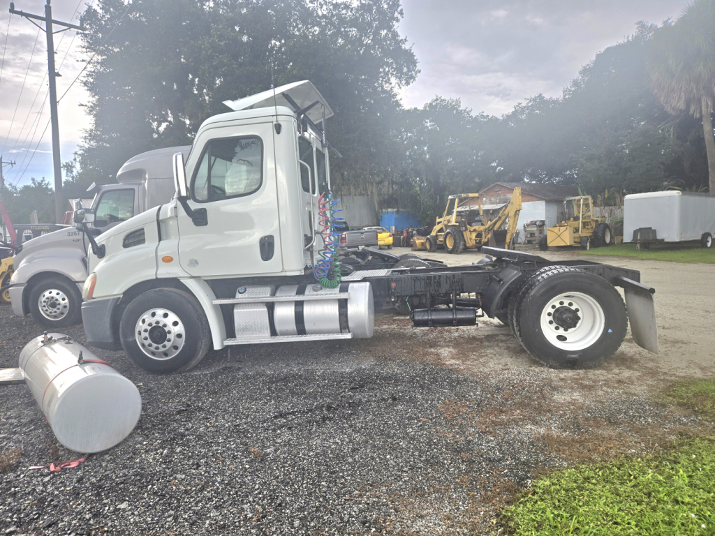 Freightliner Cascadia single-axle truck cab in side view showing engine bay area and fuel tank, with hitch and chassis exposed.