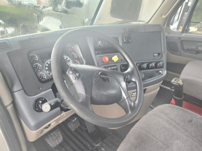 Cab interior of a Freightliner Cascadia daycab showing steering wheel, dashboard gauges, and center console.
