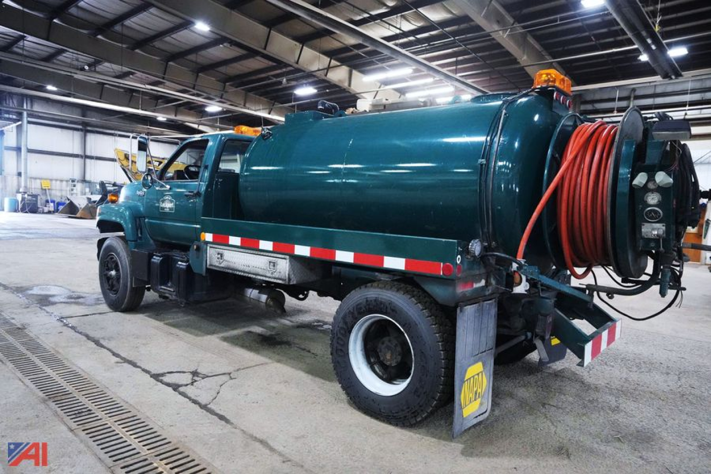GMC Topkick jetter truck with a large cylindrical tank and hose reel mounted at rear, teal body, orange hose, in-service utility vehicle.