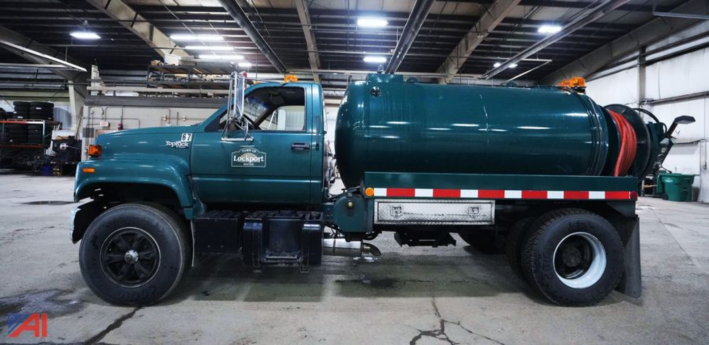 GMC Topkick SL Series vacuum/jetter truck with a 1000 gallon tank, side view showing teal body, large rear tank, orange beacon lights, and white/red reflective striping.