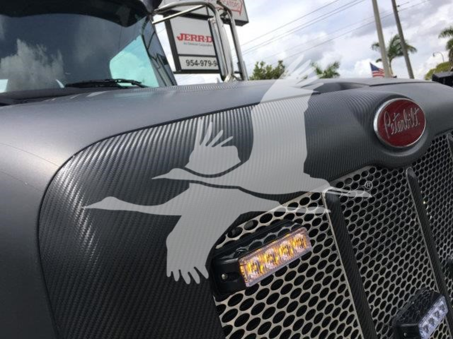 Front grille of a 2022 Peterbilt 337 with a decorative bird graphic on the hood and LED light strip in the grille area.