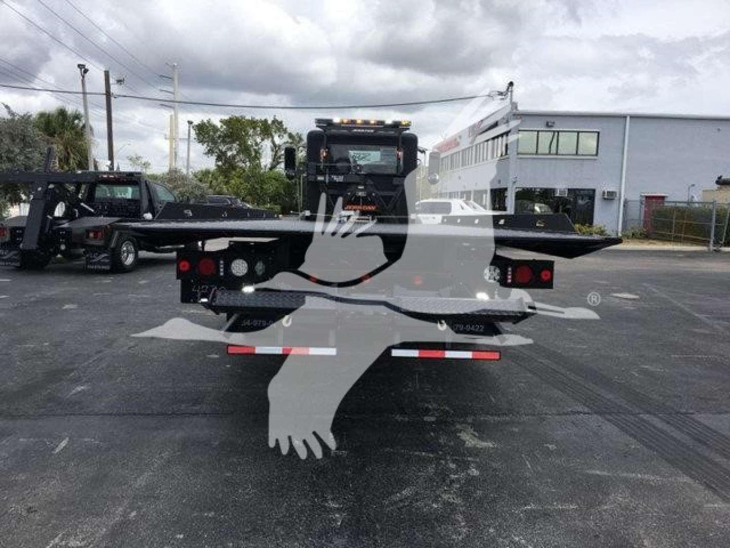 Peterbilt 337 rollback truck rear view showing hitch and mud flaps with stock number J99287 in a dealership lot.