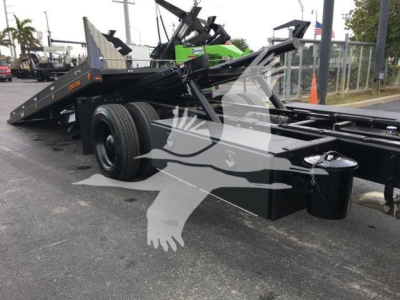 Peterbilt 337 rollback truck chassis with dual rear wheels and hydraulic frame in a dealership lot.