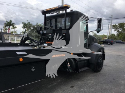 Truck side view showing Peterbilt 337 rollback truck with company branding Jerr-Dan, cab windows, black body, equipment mount, and a light bar on the roof.