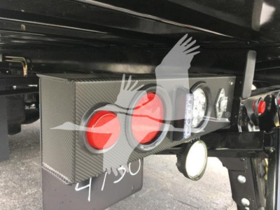 Peterbilt truck rear hitch area with rectangular metal box and red circular reflectors, grommets, and nearby lights.