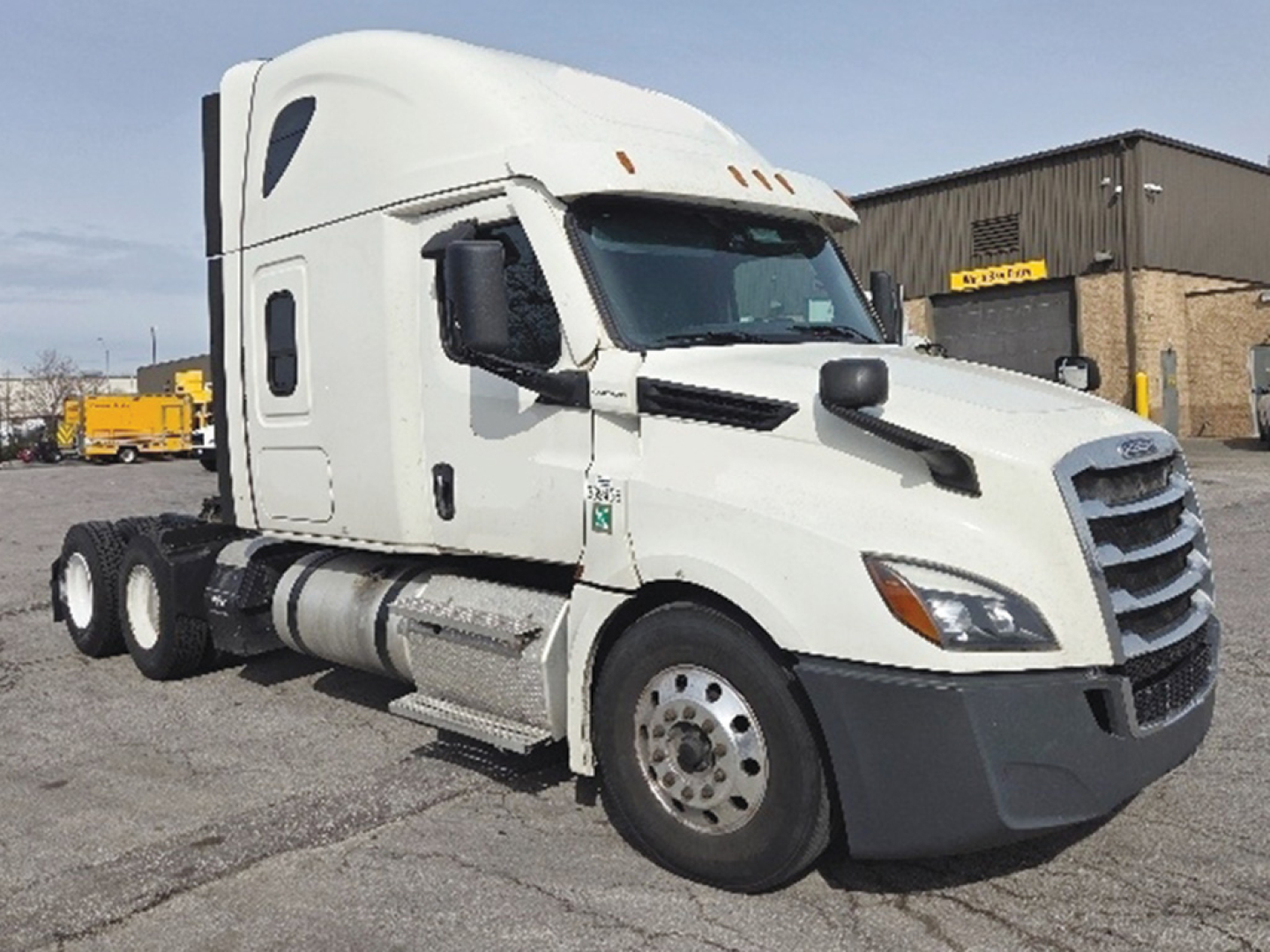 Freightliner Cascadia126 sleeper truck in a parking lot showing front and side view with white cab and dual rear axles.