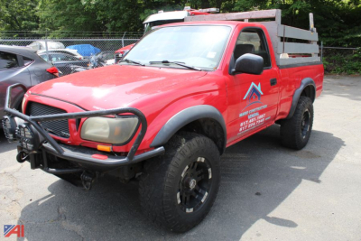 Red 2003 Toyota Tacoma pickup truck with utility bed and front grille guard, 4x4, side decals, and black off-road tires parked in lot.