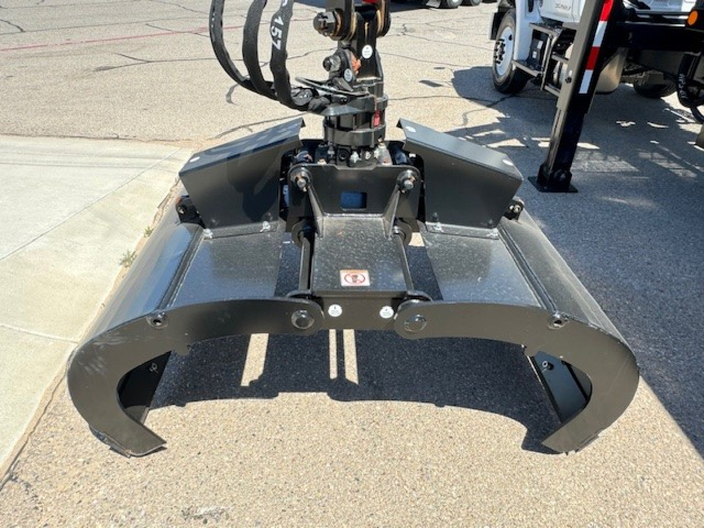 Grapple truck attachment mounted on a 2024 Hino L7 with hydraulic grapple arms visible in the foreground.
