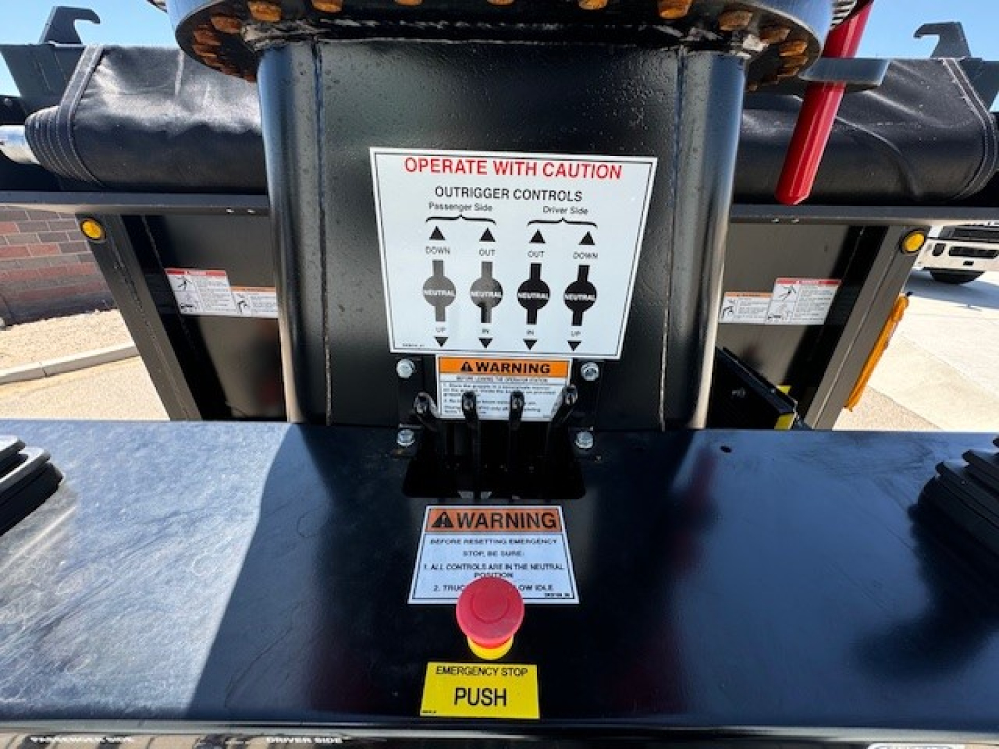 Hino L7 grapple truck control panel with labeled levers and warning stickers, emergency stop button visible.