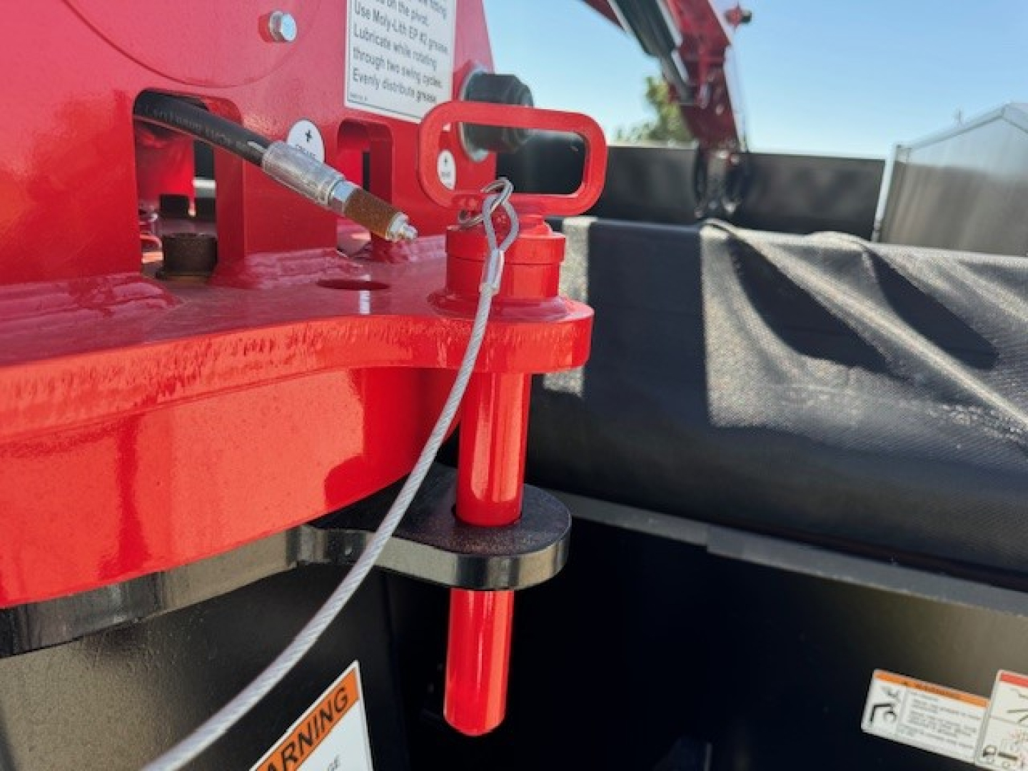 Hino L7 grapple truck showing red hydraulic linkage and safety pin with warning label.