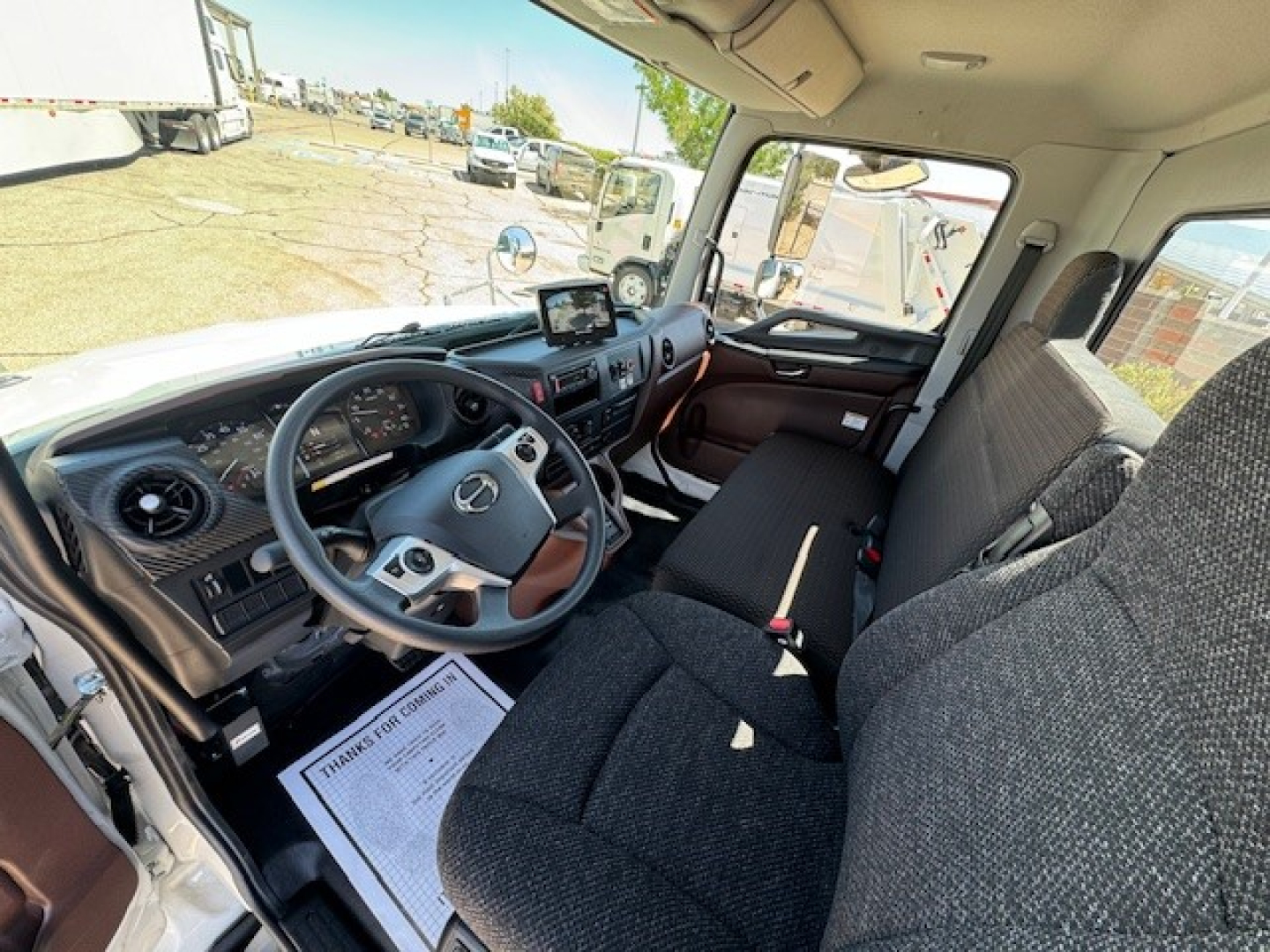 Mercedes-Benz truck interior showing steering wheel, dashboard, and front bench seat with a display screen on the dash.
