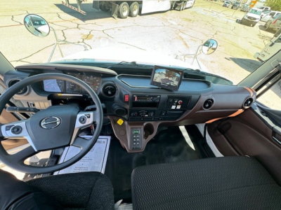 Hino L7 cab interior showing steering wheel, dashboard, large center display, gear shifter, and control panels.