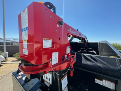 Rear-left side of a red Hino L7 grapple attachment on a truck bed, with labels and warning decals visible on the body.