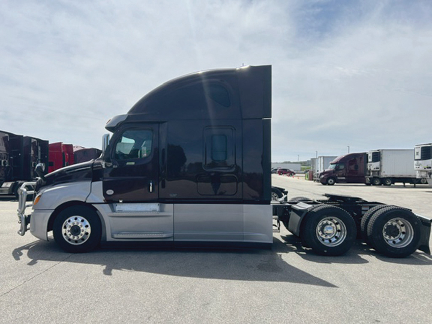 Truck side view of a Freightliner Cascadia126 sleepercab tractor in service, showing the cab and attached rear axles.