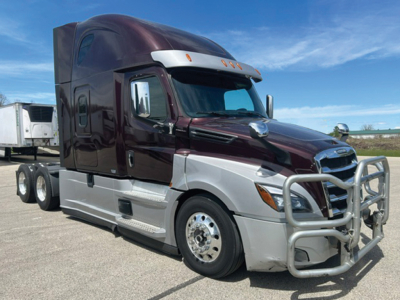 Truck cab close-up: 2021 Freightliner Cascadia126 conventional sleeper with chrome front grille guard, maroon cab, silver lower body, and side steps.