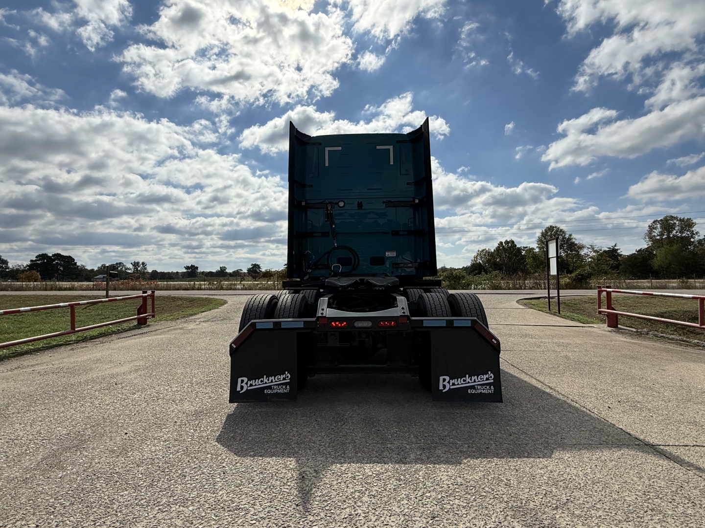 Truck rear view showing Mack PR64T76H sleeper cab in a parking lot, with blue vertical exhaust and mud flaps displaying Buckeye Trailers branding.