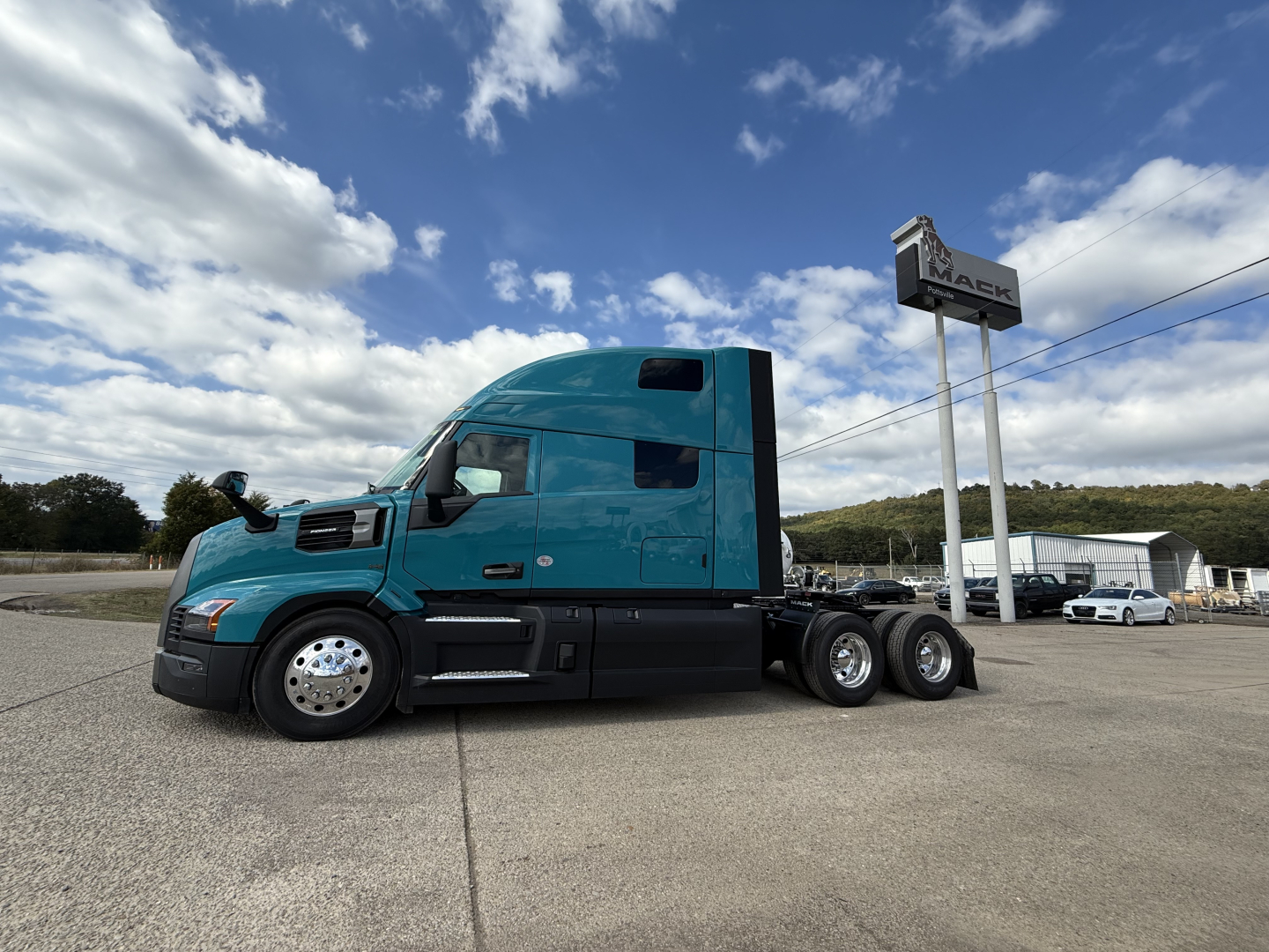 Blue Mack PR64T76H truck tractor side view showing sleeper cab and tandem rear axles.