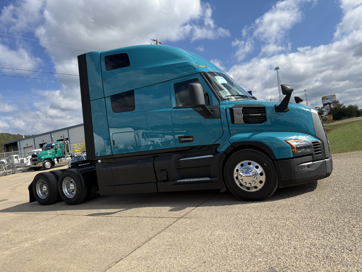 Tractor-trailer truck side view showing turquoise Mack PR64T76H with sleeper cab and dual rear axles.