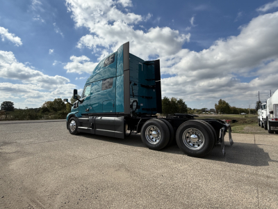 Mack PR64T76H highway tractor side view showing cab and dual rear axles with teal paint and clear lettering on the cab window area.