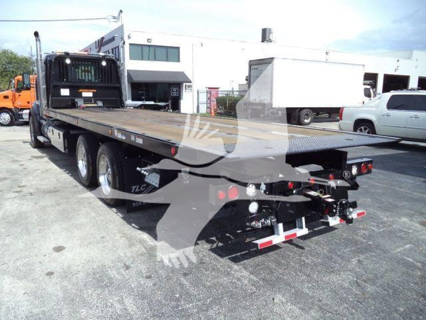 Kenworth T880 rollback truck flatbed with dual rear axles and towing equipment visible in the bed area.