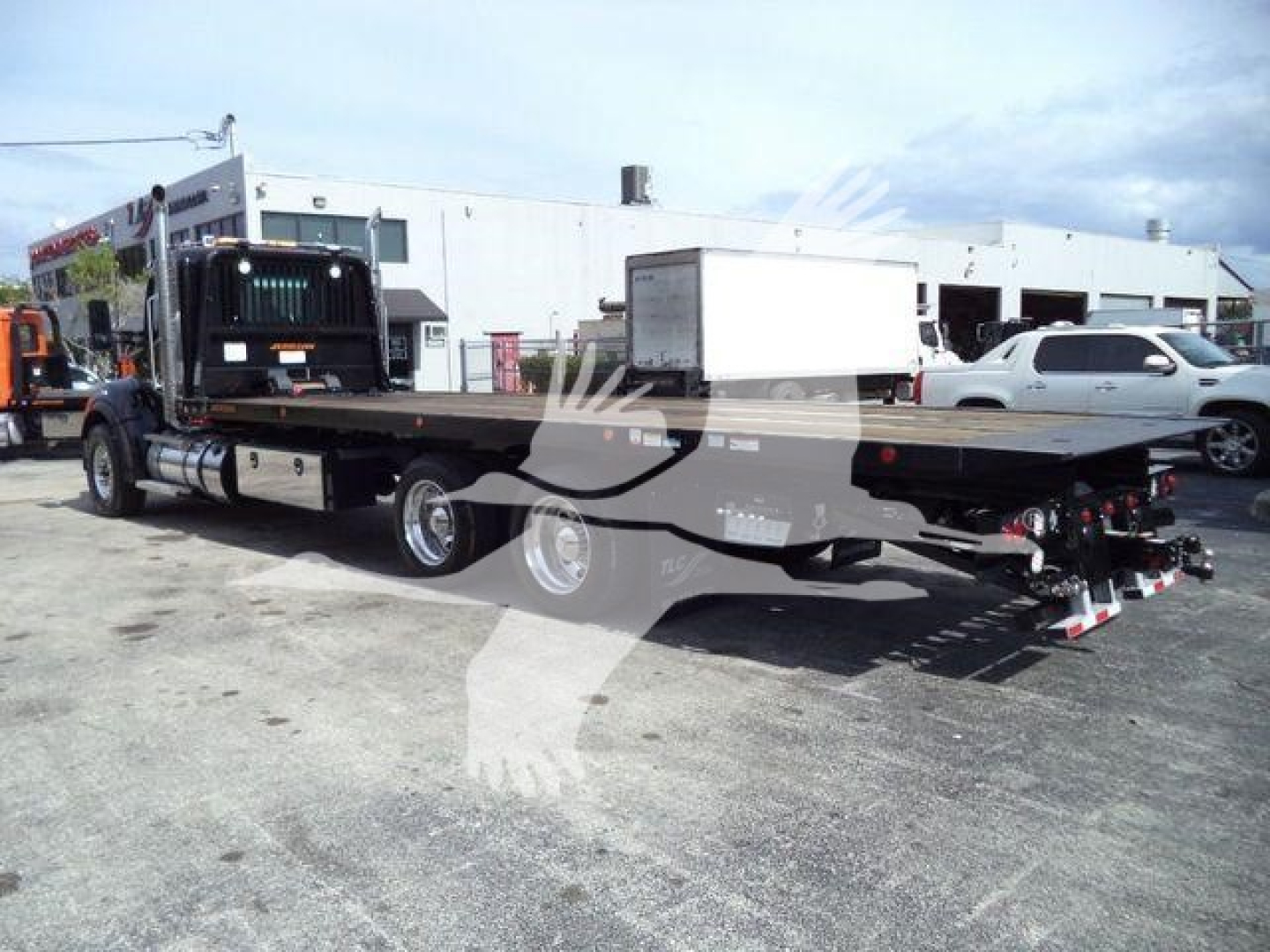 Kenworth T880 rollback truck chassis with flatbed and rear towing equipment, side view showing extended bed and dual rear axles.