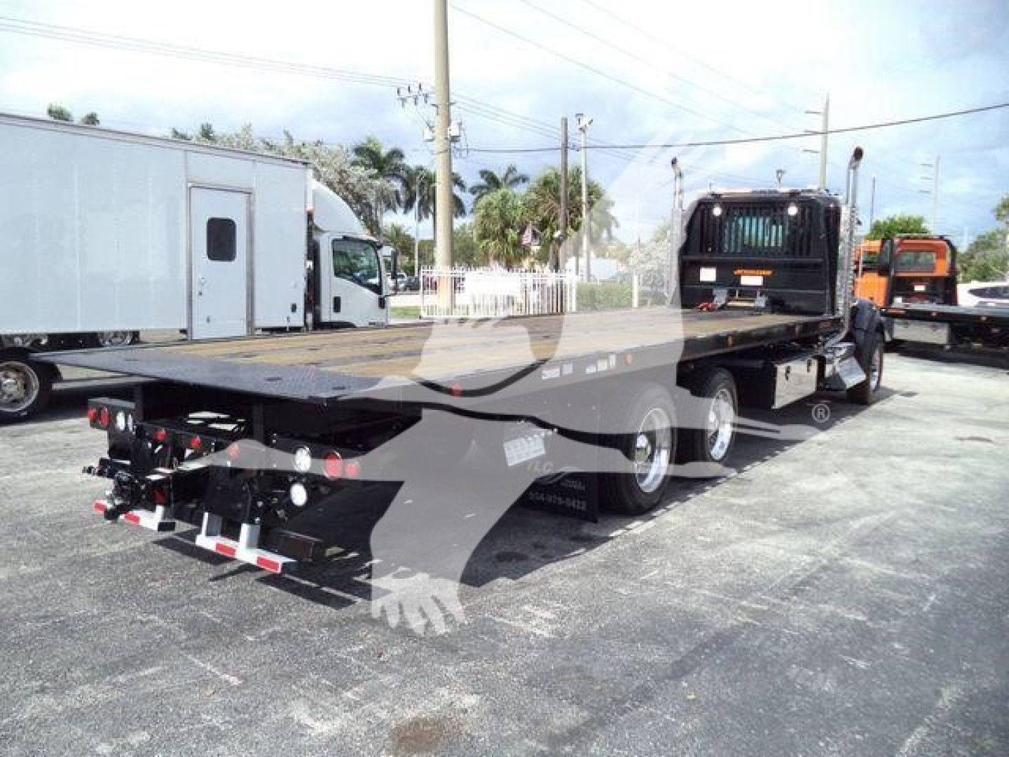 Kenworth T880 rollback truck rear view showing flatbed and triple-axle configuration.