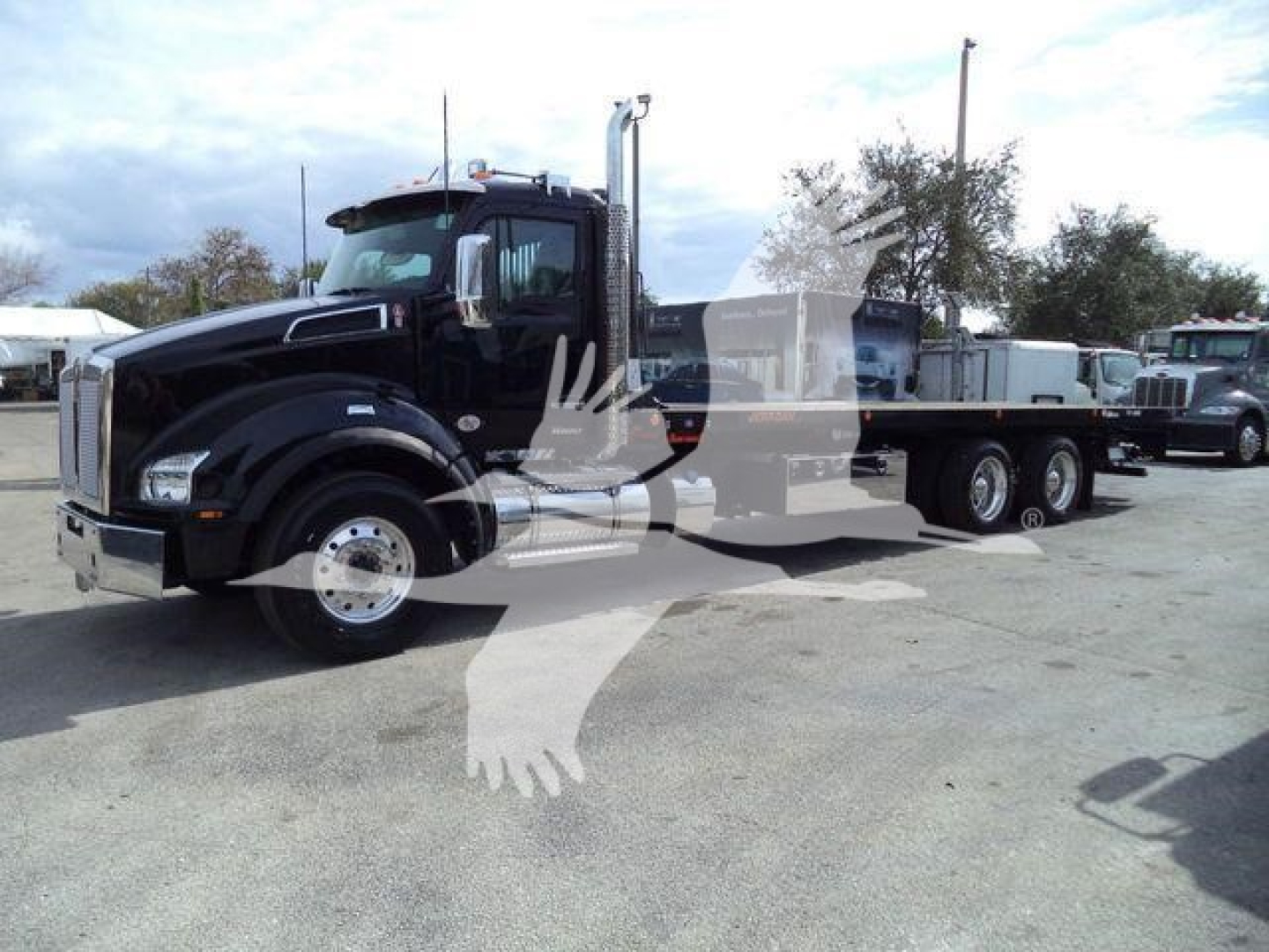 Kenworth T880 rollback truck in view showing cab and chassis with dual rear axles and a long bed.