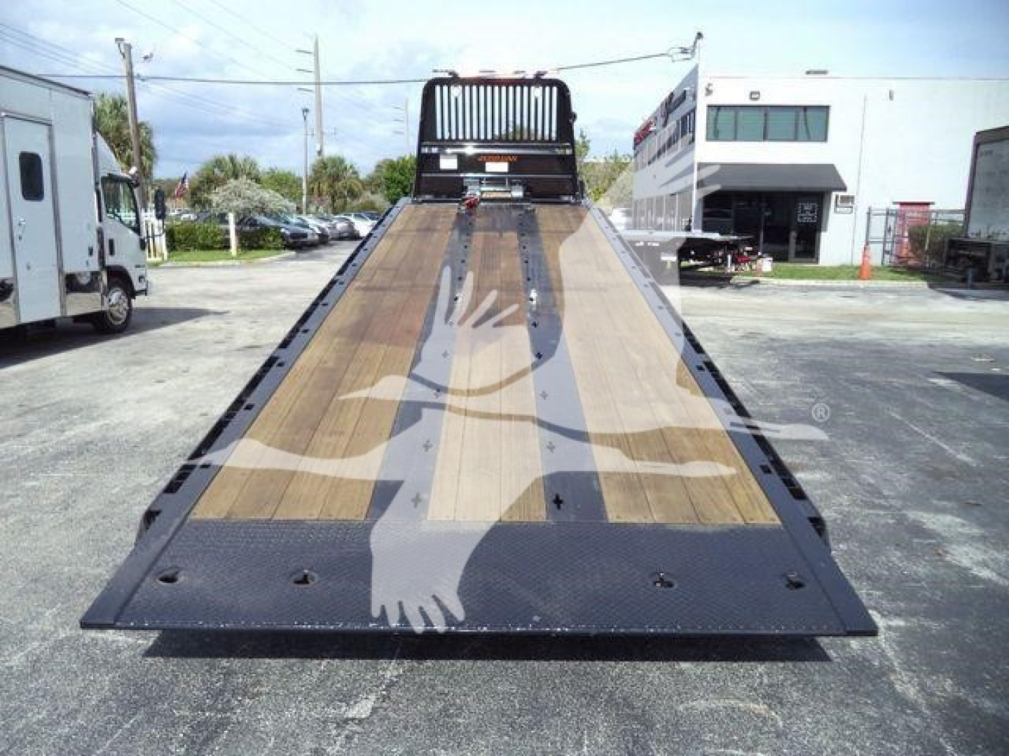 Kenworth T880 rollback bed on a flatbed tow truck with wooden deck and steel ramp side rails.