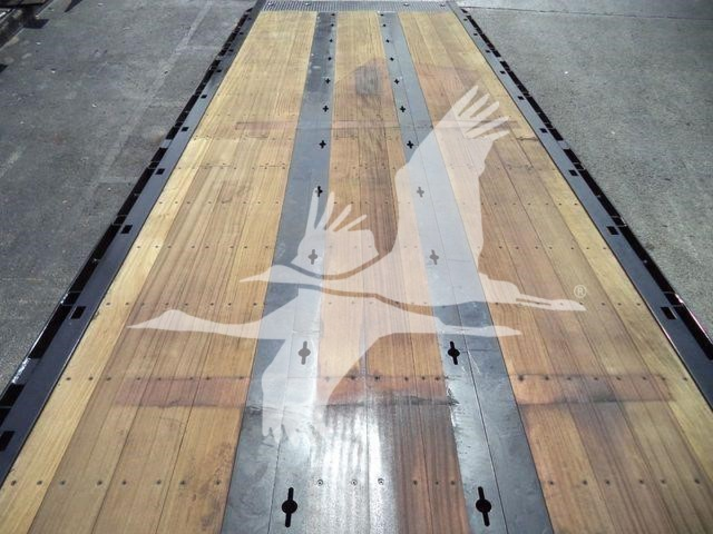 Long wooden rollback deck with metal side rails, Kenworth logo watermarked on image, no visible text on equipment.