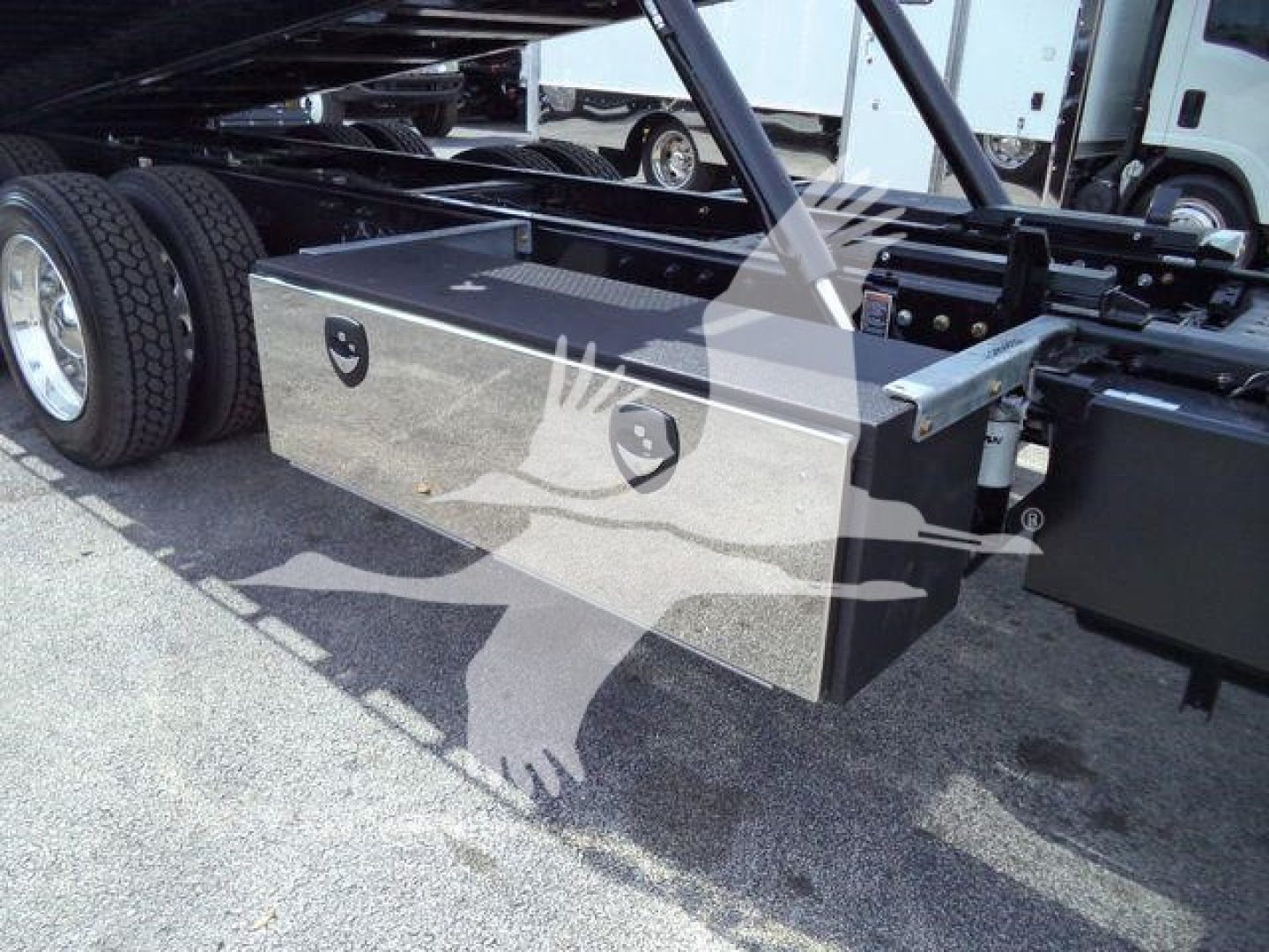 Kenworth T880 rollback truck chassis showing a metal toolbox mounted under the frame with dual latches.