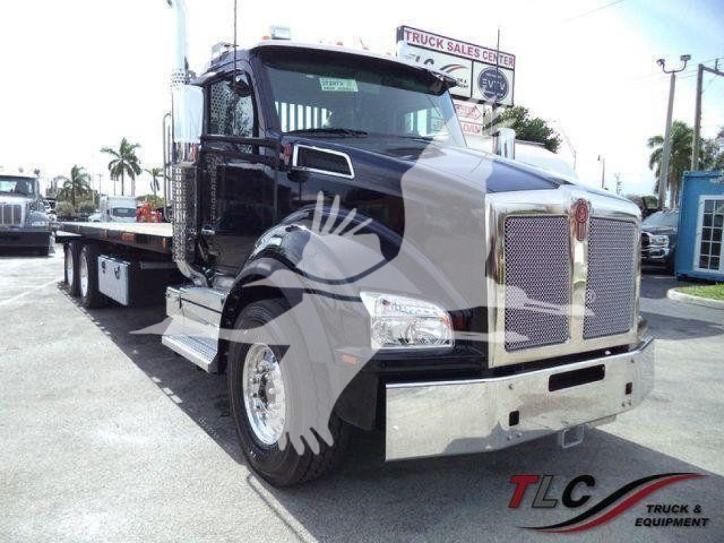 Kenworth T880 rollback truck in dark color showing front grille, dual headlights, chrome bumper, and chrome wheels.